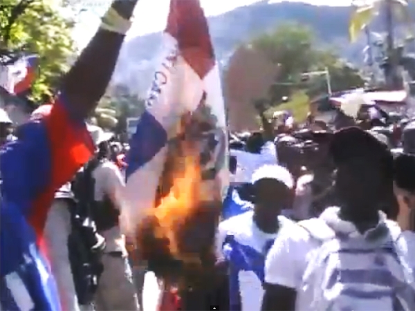 Momentos en que la Bandera Dominicana era quemada por un grupo de haitianos que dicen representar organizaciones de la sociedad civil haitiana en Puerto Príncipe.