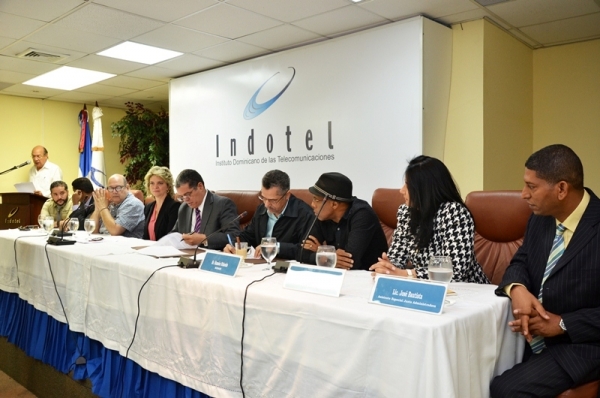 El presidente del Indotel, licenciado Carlos Amarante Baret, y el presidente de la SGACEDOM, diputado Manuel Jiménez, mientras firman el convenio de colaboración para la protección del derecho de autor en el sector de las telecomunicaciones
