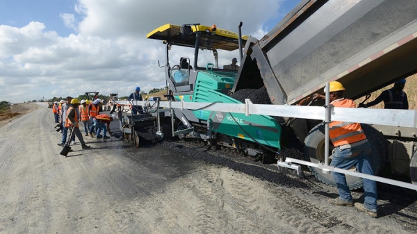 Obreros del Ministerio de Obras Públicas en plena ejecución de asfaltado de una carretera en República Dominicana.