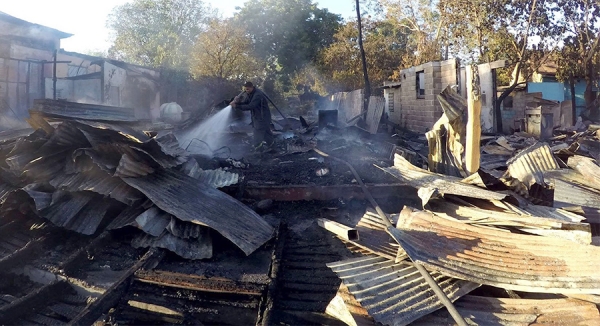 Un bombero utiliza su manguera de agua a presión para sofocar el fuego del PTD en Azua y otras tres casas.