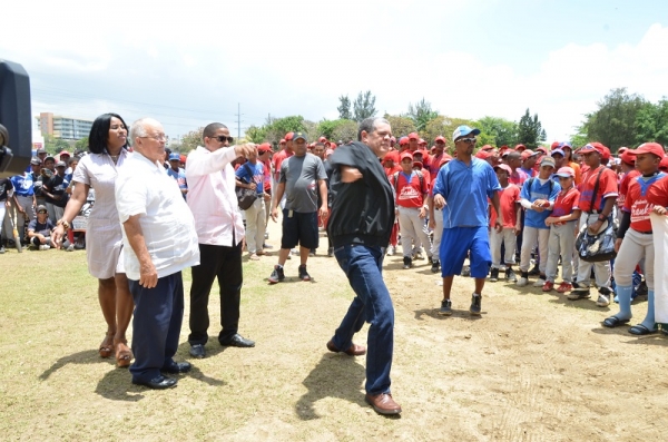 Carlos Amarante Baret, director del Indotel, realiza el lanzamiendo de honor en la apertura del torneo 20 Aniversario de la Academia de Béisbol Franklin Rodríguez. Observan la magistrada Claribel Nivar y el presidente de la academia que lleva su nombre. 