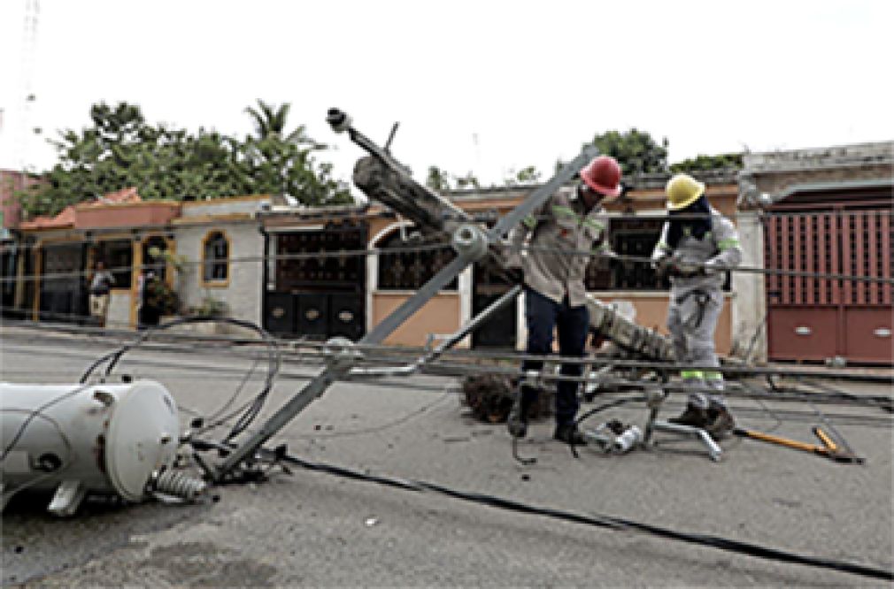 Obreros de Edeeste trabajan con uno de los postes derribado por el camión volteo en El Brisal, de Santo Domingo Este.