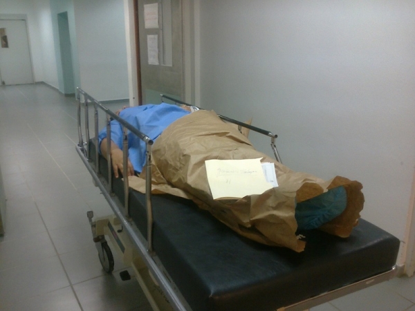 Un paciente en una camilla en el hospital Calventi espera en un pasillo arropado con papel. 