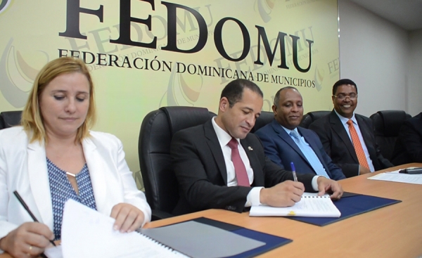 Antonia Calvo y Juan de los Santos mientras firman el convenio. Observan Rafael Germosén y Víctor D´Aza.