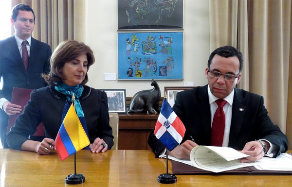 El canciller dominicano, arquitecto Andrés Navarro, firma el acuerdo acompañado de la canciller de Colombia, María Ángela Holguín