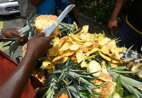 Vendedor callejero pelando piña.
