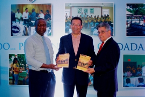 Johnny Jones, entrega un ejemplar del Clud de Tocayo, al presentador de noticias Félix Victorino y al politólogo José Rijo en la presentación de su obra en el stand de la LMD en la Feria del Libro