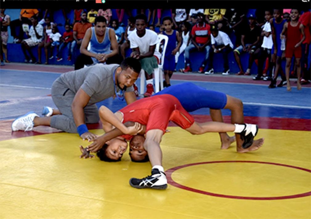 Un árbitro mira a dos niños en un momento crucial de la pelea entre dos niños atletas.
