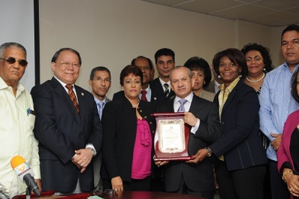 El ministro de Salud Pública recibe una placa de reconocimiento de parte de Amarilis Herrera y Pedro Sing, junto a otros miembros del Consejo Directivo del CMD. 