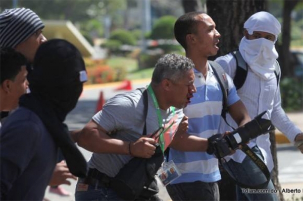 El fotoperiodista Danny Polanco corre con su ojo herido en busca de atención urgente para salvar su rostro.