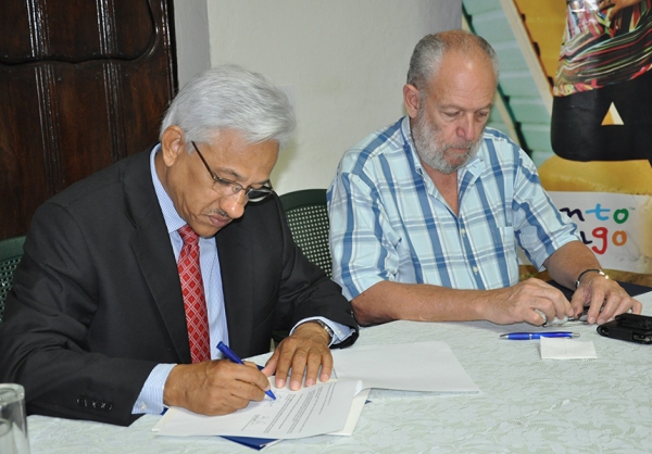 Osvaldo Soriano, en representación de ADROMPRETUR, y Freddy Ginebra, presidente del Cluster Turístico de Santo Domingo, mietrnas firman el acuerdo.