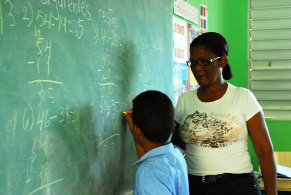 Profesora enseñando matemáticas a un niño en una escuela.