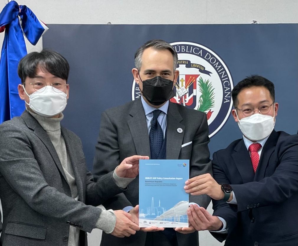 Momento en que los doctores Hokyung Bang, Director de Consultas Políticas del Instituto de Desarrollo de Corea y Junyoung Kim, Presidente Ejecutivo de la Red Global Tantan, entregaban al Embajador Federico Cuello Camilo el informe final sobre República Dominicana del estudio para compartir conocimientos sobre las industrias electrónicas y de dispositivos médicos en las zonas francas dominicanas.