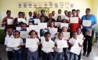 Niños, niñas y adultos graduados de informática en una sala digital de Oviedo, Barahona.