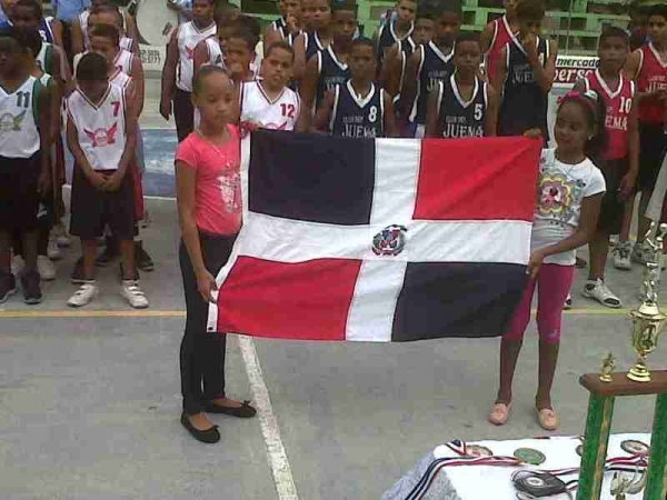 Dos niñas muestran el simbolo patrio durante el desfile para dar inicio al torneo de baloncesto de diferentes categorias en Azua, organizado por el Clud Deportivo Juventud en Marcha (JUVEMA)