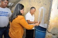 La ministra de trabajo, Maritza Hernández, explica a uno de las residentes de los sectores del operativo como se elimina los criaderos de mosquitos