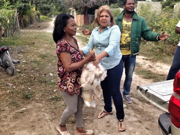 Una señora de las tantas familias que se beneficiaron con el reparto recibe varios pollos para la cena navideña