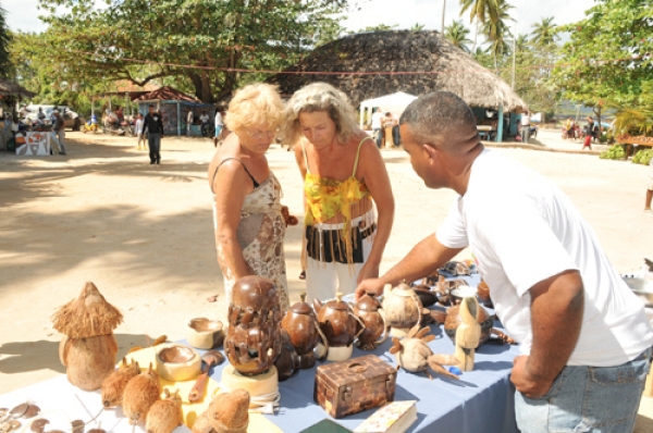 Turistas observan artesanía hecha con jícara de coco, realizada por artesanos de Samaná.
