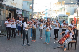 La artista Venus Guerrero, directora de la Orquesta Municipal de Violines, con un grupo de niños y niñas tocándo en un barrio populoso del municipio Sosúa en la provincia Puerto Plata. 