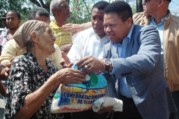 El administrador general de los Comedores Económicos, licenciado Ramón Monchy Rodríguez entrega una ración cruda a una señora de escasos recursos.