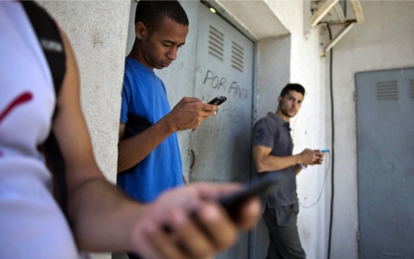 Varios estudiantes se reúnen detrás de un local en busca de señal de Internet para sus teléfonos multiuso en La Habana, Cuba. 